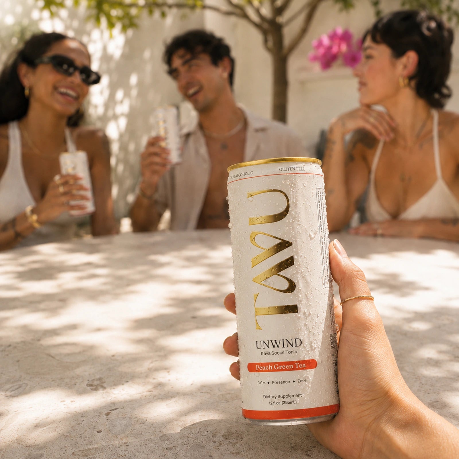 Hand holding a chilled can of TAVU Unwind Peach Green Tea